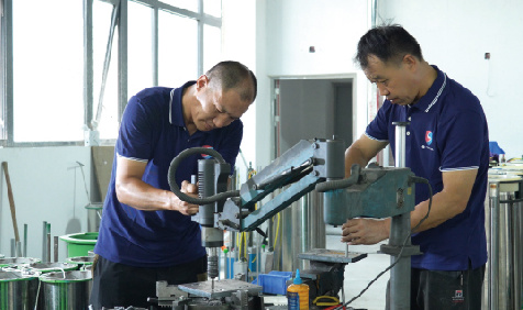 Workers machining and inspecting rising bollard components in the workshop
